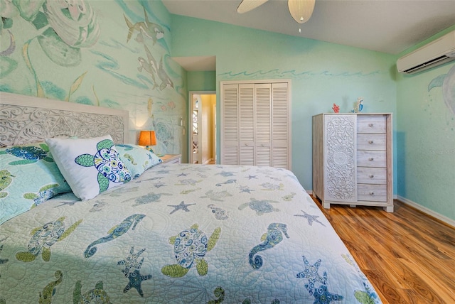 bedroom with lofted ceiling, a closet, a wall mounted AC, a ceiling fan, and wood finished floors