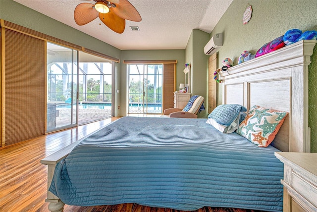 bedroom featuring visible vents, a sunroom, an AC wall unit, wood finished floors, and access to outside