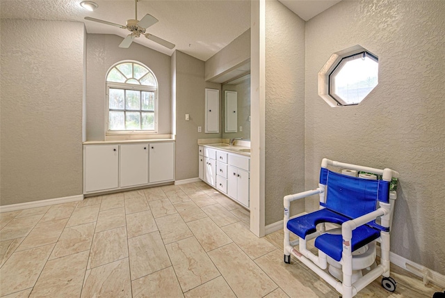 bathroom with vaulted ceiling, a textured wall, and vanity