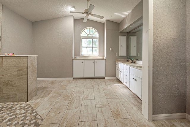 bathroom with a textured wall, lofted ceiling, wood tiled floor, a textured ceiling, and a sink