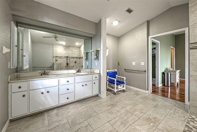 full bath featuring double vanity, a shower stall, a sink, and a textured wall