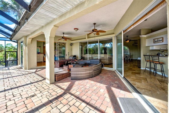 view of patio / terrace featuring glass enclosure, an outdoor hangout area, and a ceiling fan