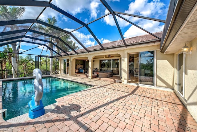 outdoor pool with an outdoor hangout area, glass enclosure, a patio area, and a ceiling fan