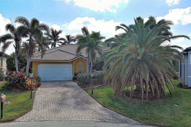 view of front of house featuring a garage, a front yard, decorative driveway, and stucco siding