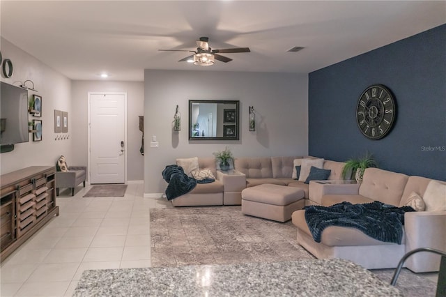 living area featuring a ceiling fan, visible vents, baseboards, and light tile patterned floors