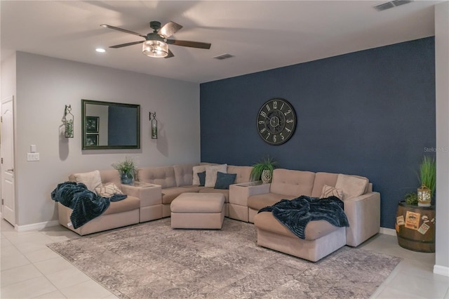 tiled living room featuring ceiling fan, an accent wall, visible vents, and baseboards