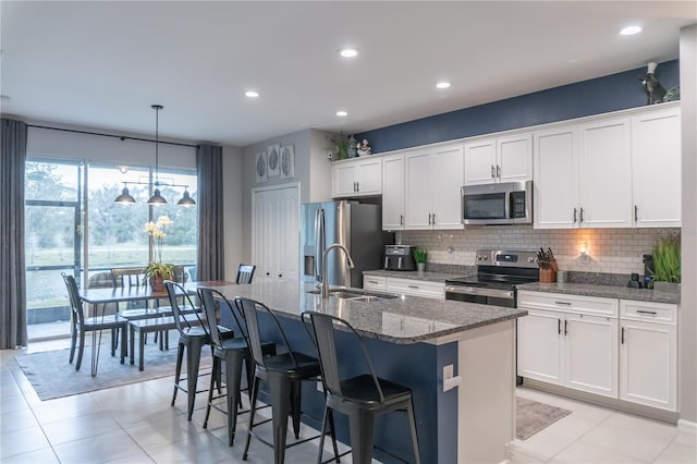 kitchen with a kitchen island with sink, appliances with stainless steel finishes, decorative backsplash, and a sink