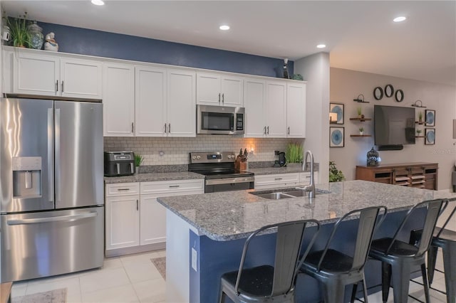 kitchen with a breakfast bar area, appliances with stainless steel finishes, white cabinets, and a sink