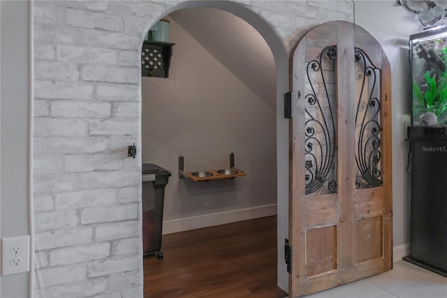 interior space featuring baseboards, arched walkways, and wood finished floors