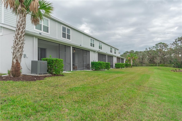 back of property featuring central air condition unit, a sunroom, and a yard