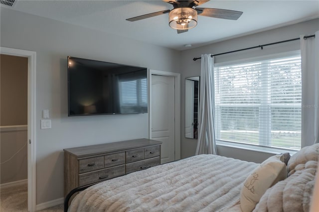 carpeted bedroom featuring multiple windows, a ceiling fan, and baseboards