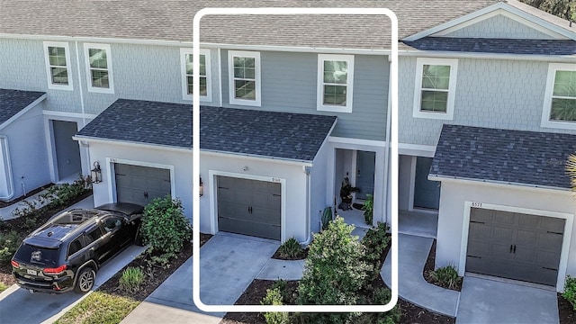 townhome / multi-family property featuring a garage, driveway, roof with shingles, and stucco siding