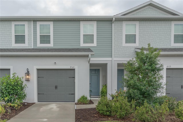 townhome / multi-family property with a shingled roof and stucco siding