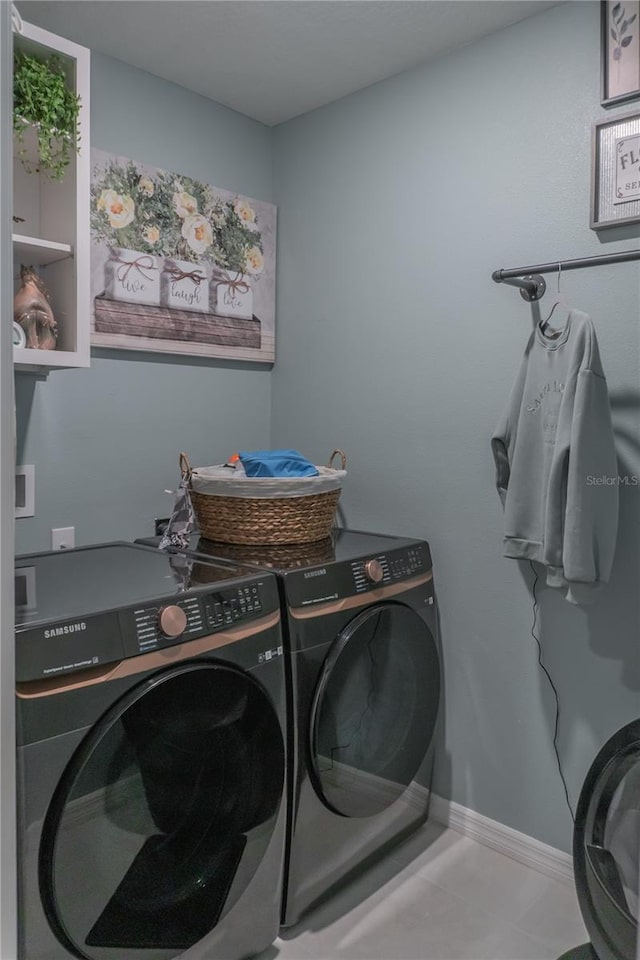 clothes washing area with laundry area, baseboards, and washer and clothes dryer