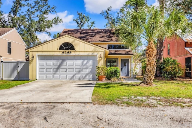 view of front facade with a garage, driveway, a front lawn, and fence