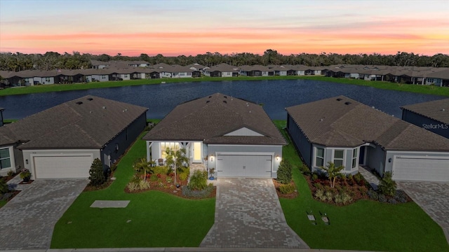 aerial view at dusk featuring a water view and a residential view