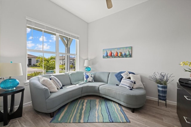 living area featuring a ceiling fan, wood tiled floor, and baseboards