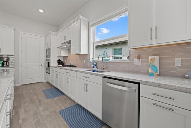 kitchen featuring under cabinet range hood, a sink, white cabinetry, appliances with stainless steel finishes, and light stone countertops