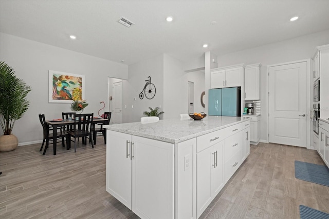 kitchen with visible vents, appliances with stainless steel finishes, a center island with sink, and white cabinets