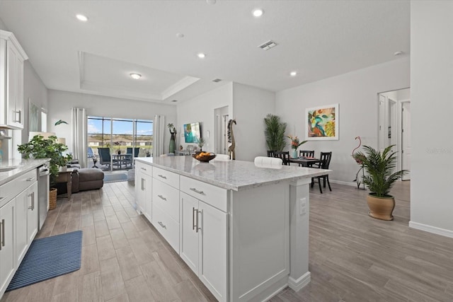 kitchen featuring a kitchen island, visible vents, white cabinetry, open floor plan, and dishwasher