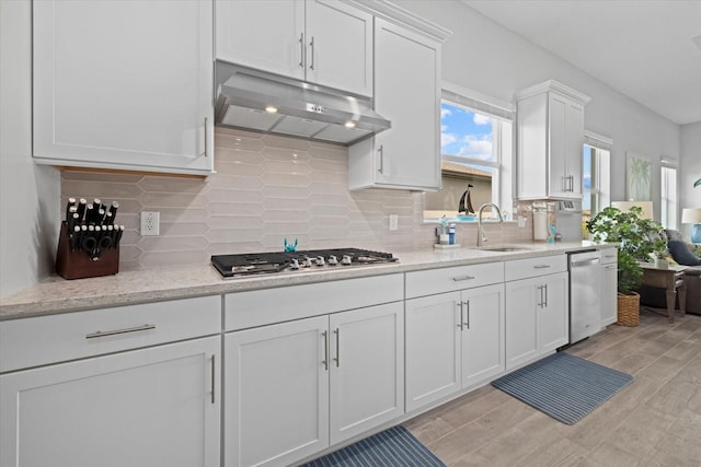 kitchen featuring under cabinet range hood, stainless steel appliances, a sink, white cabinets, and light wood-type flooring