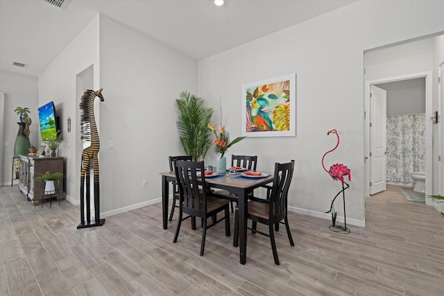 dining room featuring baseboards, visible vents, and light wood finished floors