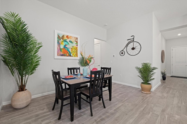 dining area featuring light wood finished floors, recessed lighting, and baseboards