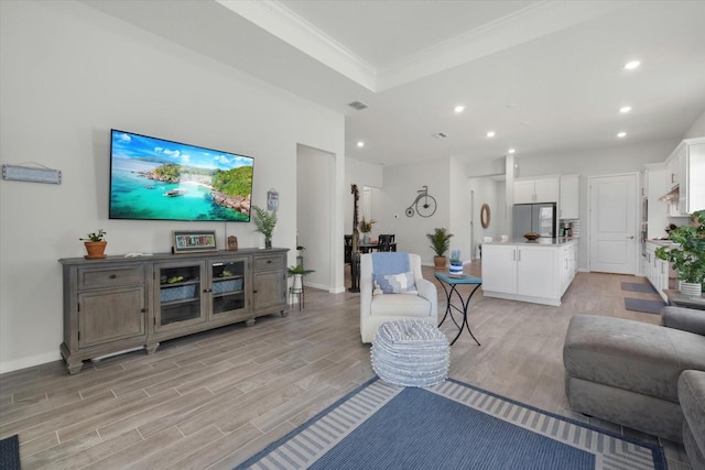 living area featuring recessed lighting, a raised ceiling, visible vents, light wood-style floors, and baseboards