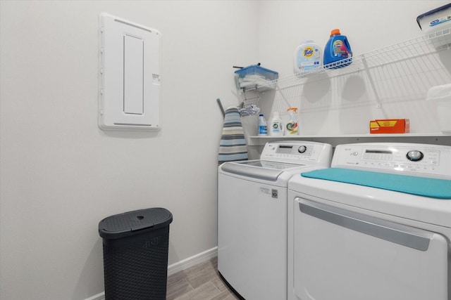 laundry area featuring laundry area, electric panel, baseboards, wood tiled floor, and separate washer and dryer