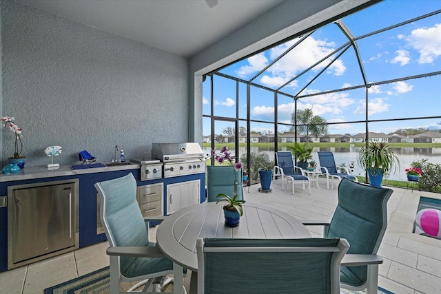 view of patio with a water view, glass enclosure, a grill, and an outdoor kitchen