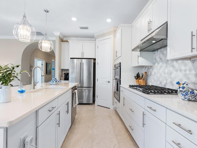 kitchen with stainless steel appliances, light countertops, white cabinets, a sink, and under cabinet range hood