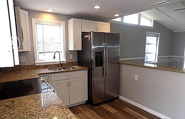 kitchen featuring dark wood-type flooring, white cabinets, stone counters, stainless steel refrigerator with ice dispenser, and sink