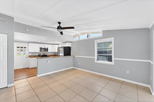 kitchen featuring a peninsula, white cabinetry, a ceiling fan, vaulted ceiling, and appliances with stainless steel finishes