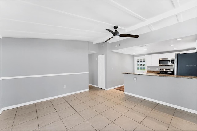 kitchen with vaulted ceiling with beams, stainless steel appliances, white cabinets, ceiling fan, and baseboards