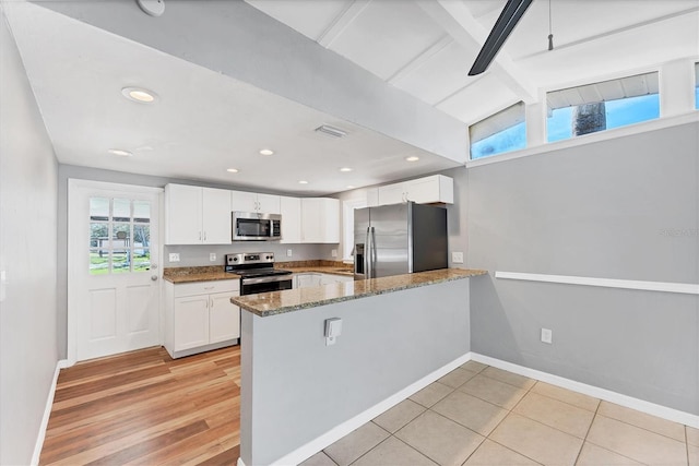 kitchen featuring stone counters, stainless steel appliances, white cabinetry, a peninsula, and baseboards