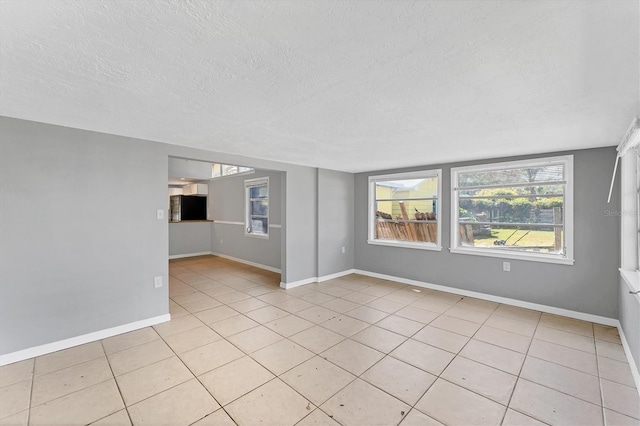 unfurnished room featuring light tile patterned floors, baseboards, and a textured ceiling