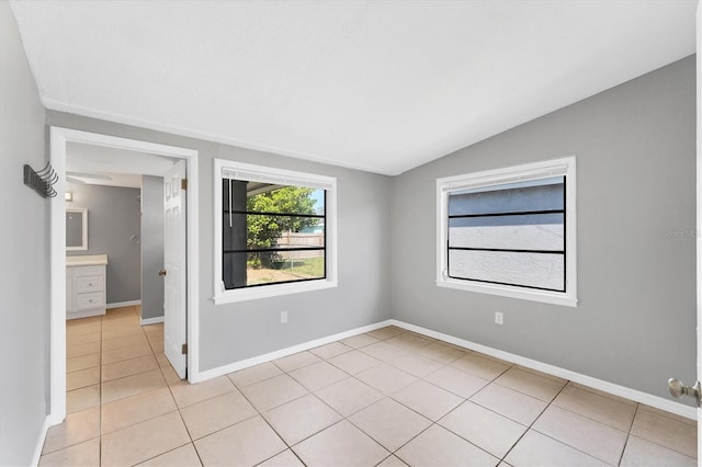 spare room featuring vaulted ceiling, baseboards, and light tile patterned floors