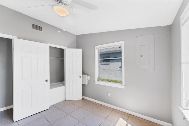 unfurnished bedroom with light tile patterned floors, a closet, visible vents, electric panel, and baseboards