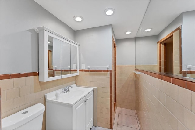 bathroom featuring wainscoting, vanity, tile walls, and recessed lighting