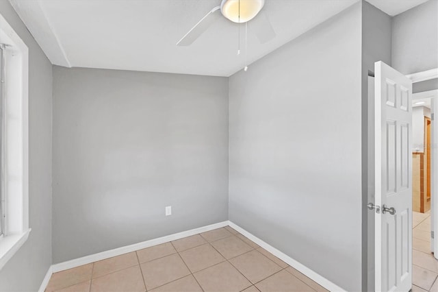 empty room featuring baseboards, a ceiling fan, and light tile patterned flooring