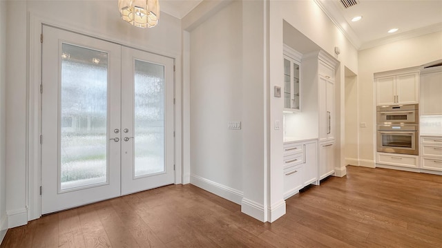 doorway to outside with french doors, crown molding, baseboards, and wood finished floors