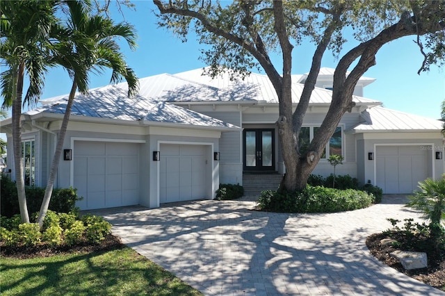 view of front of property featuring a standing seam roof, an attached garage, french doors, and metal roof