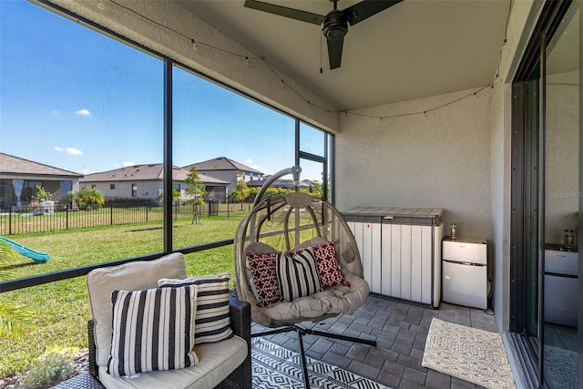 sunroom / solarium with a residential view and a ceiling fan