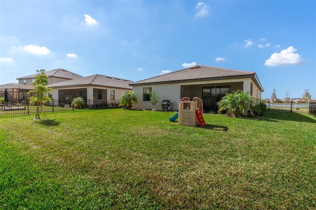 rear view of property featuring a yard, a fenced backyard, and stucco siding