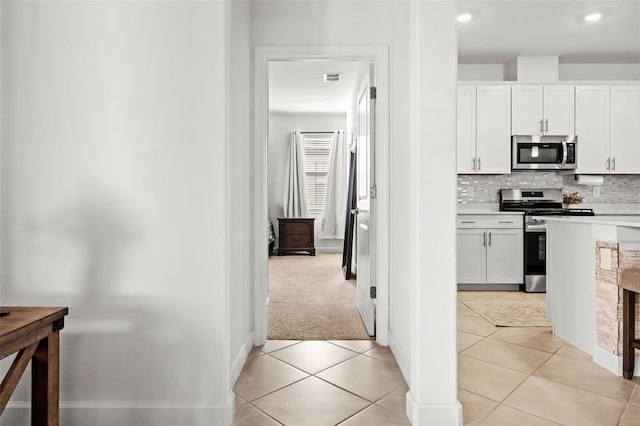 kitchen featuring appliances with stainless steel finishes, light countertops, white cabinetry, and light tile patterned floors