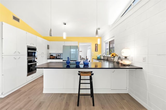 kitchen featuring dark countertops, visible vents, freestanding refrigerator, white cabinetry, and a sink