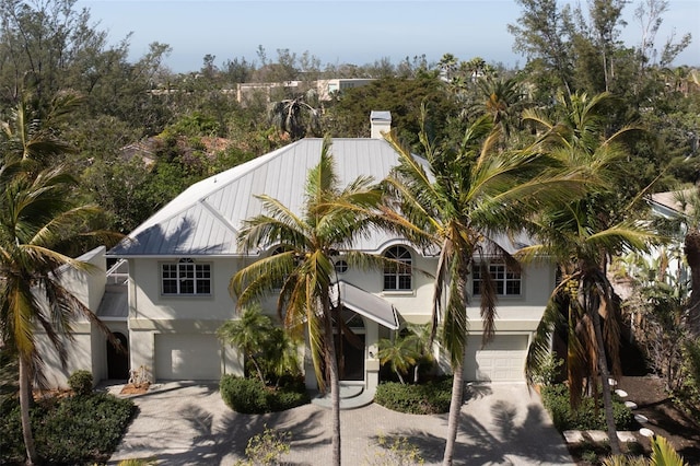 view of front of property with an attached garage, metal roof, concrete driveway, and stucco siding