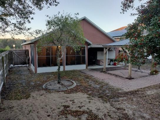 rear view of property with a patio area, a fenced backyard, a sunroom, and a gazebo