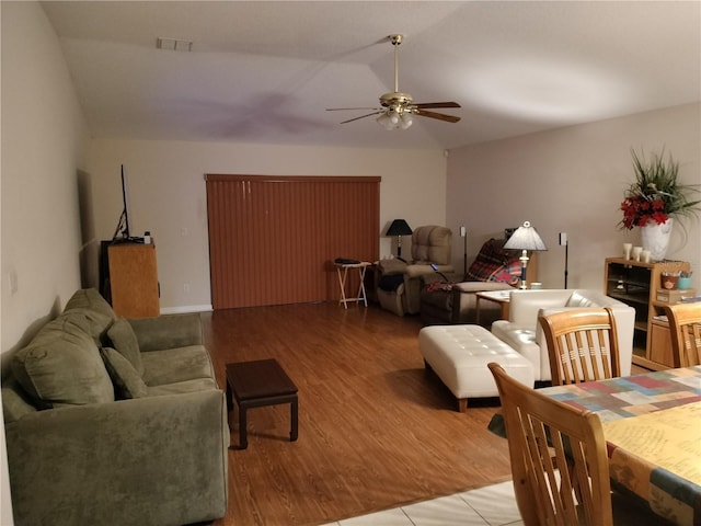 living room with ceiling fan, visible vents, vaulted ceiling, and wood finished floors