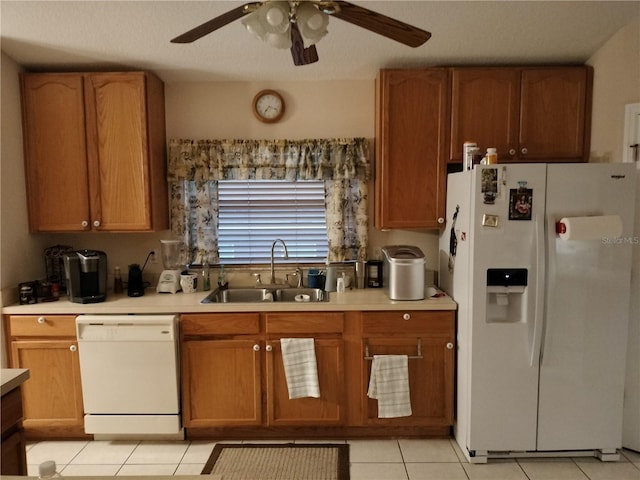 kitchen with light tile patterned floors, light countertops, brown cabinetry, a sink, and white appliances